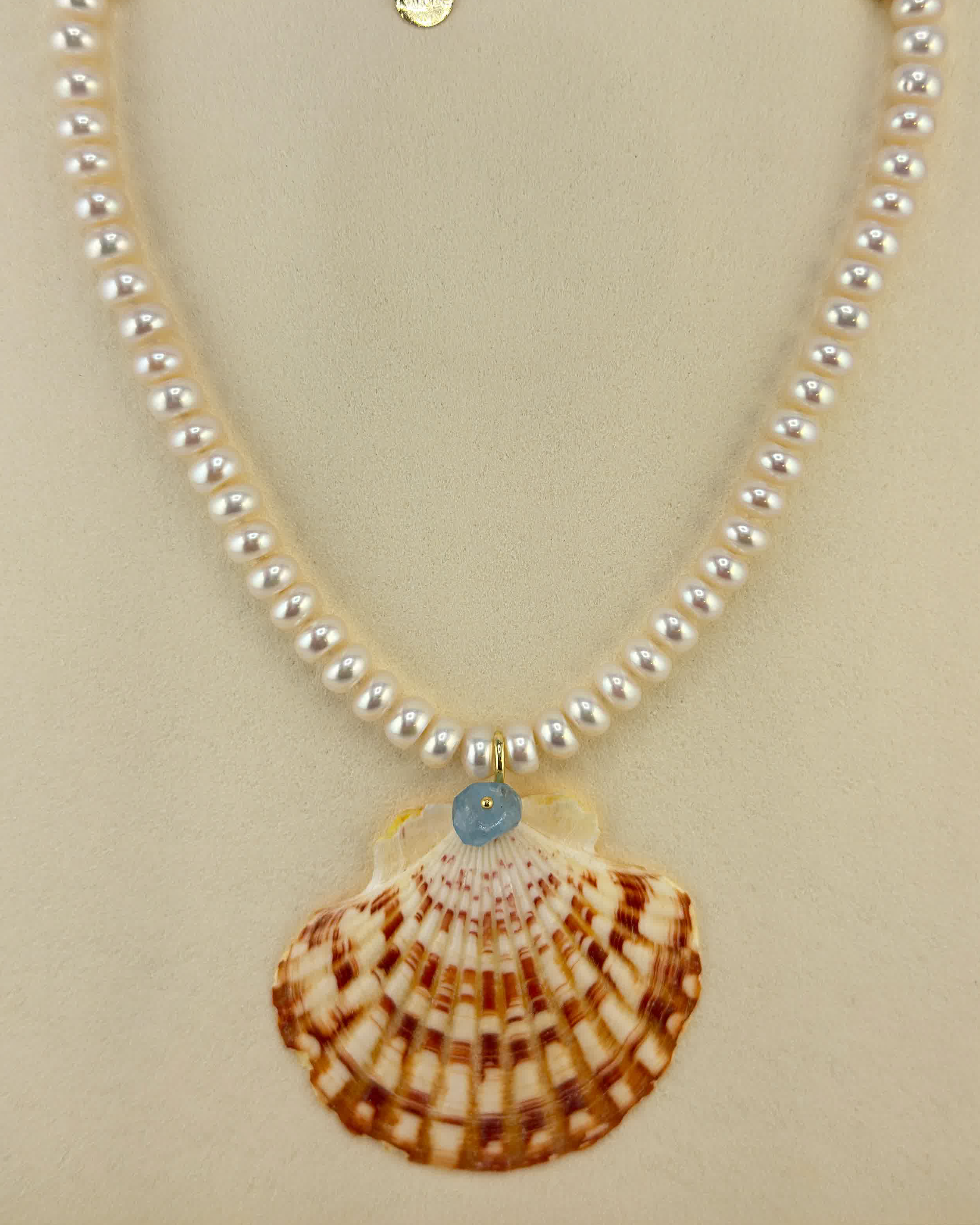 Pearl necklace with a shell pendant on a beige card