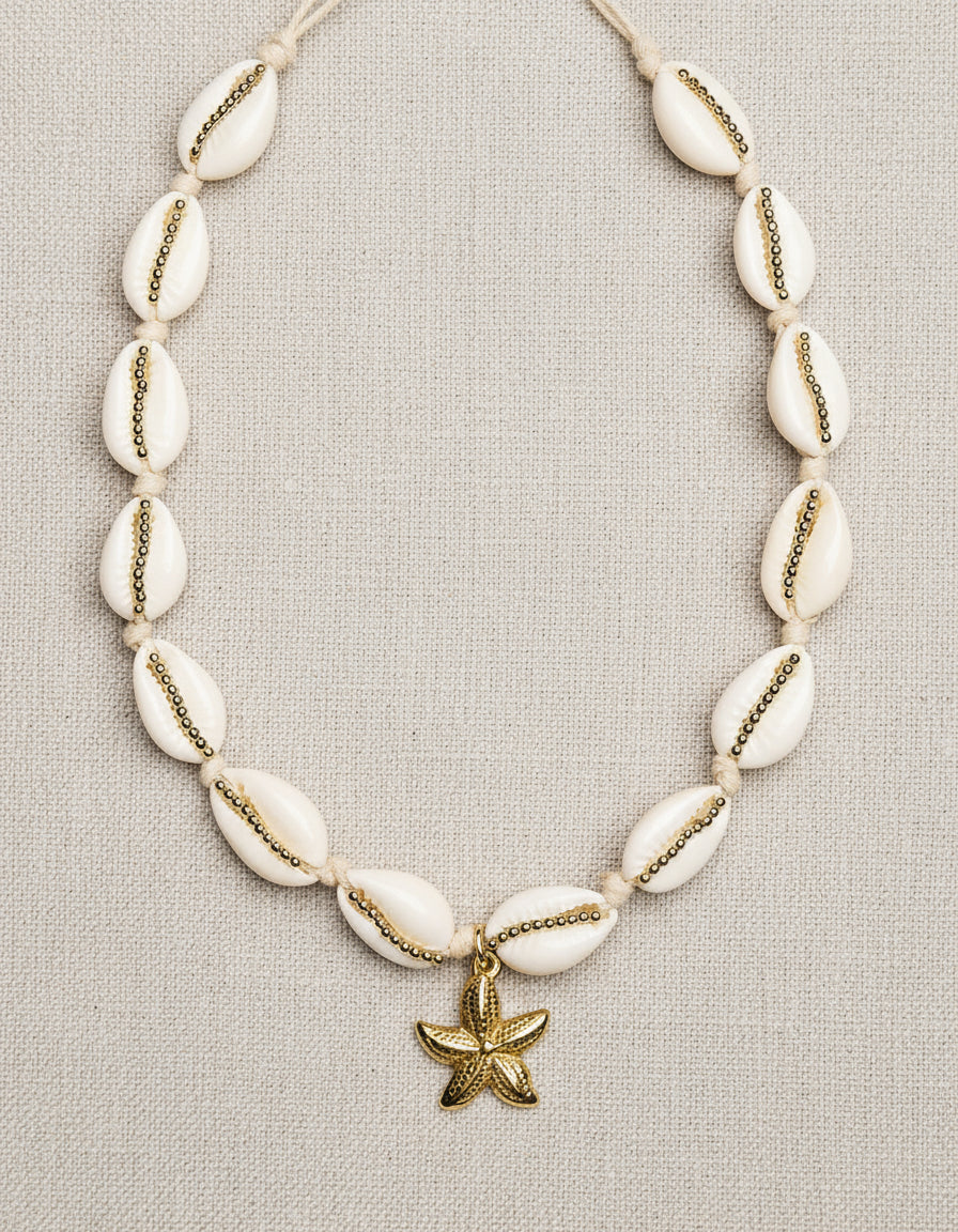 Necklace with white beads and a gold starfish charm on a white background