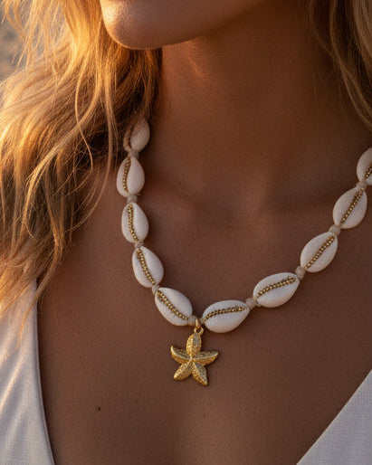 Necklace with white beads and a gold starfish charm on a white background
