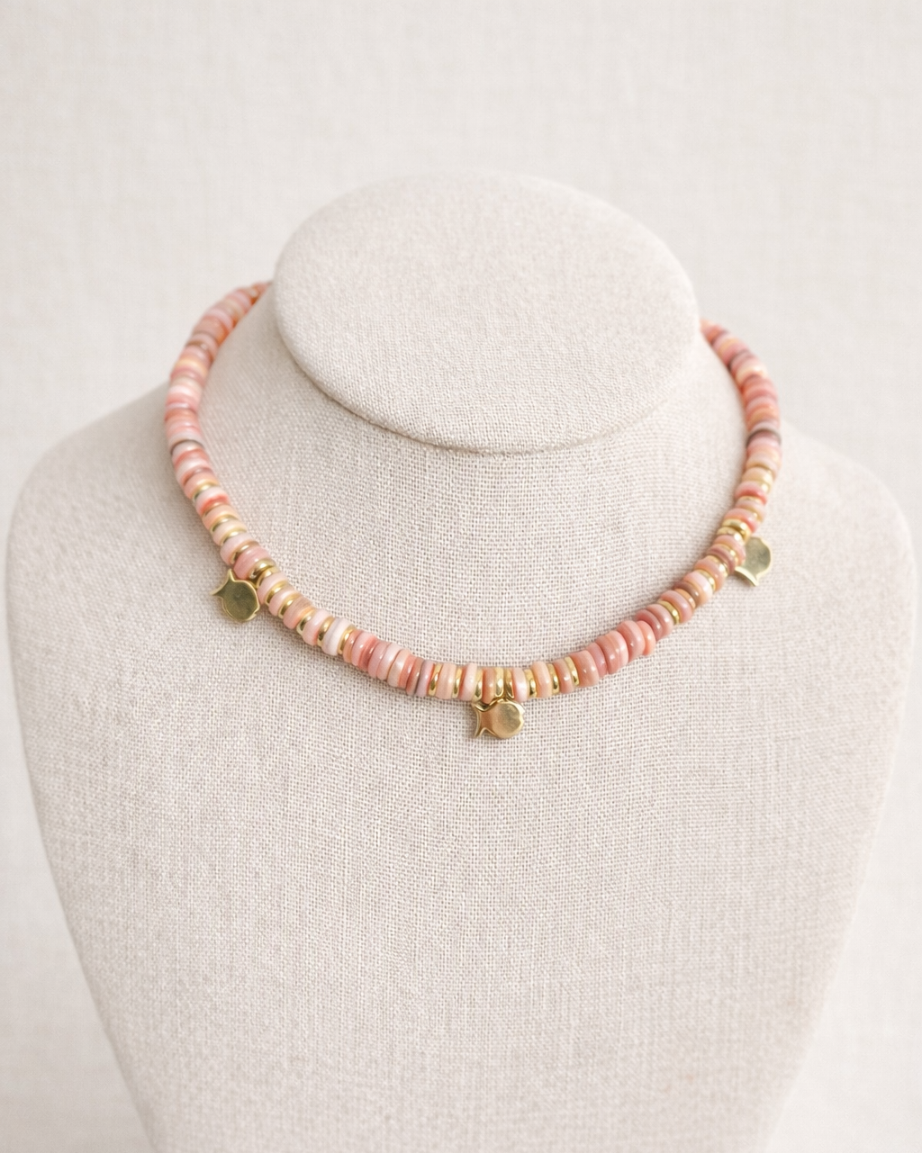 Necklace with pink beads on a mannequin bust against a white background
