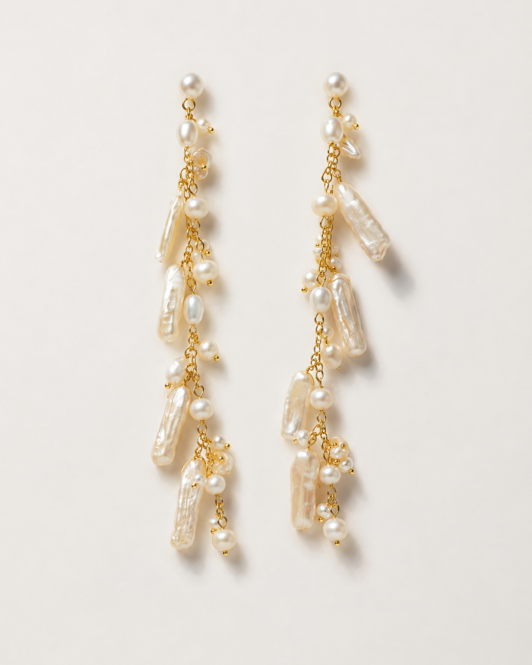 Pair of pearl earrings with gold chains on a light background