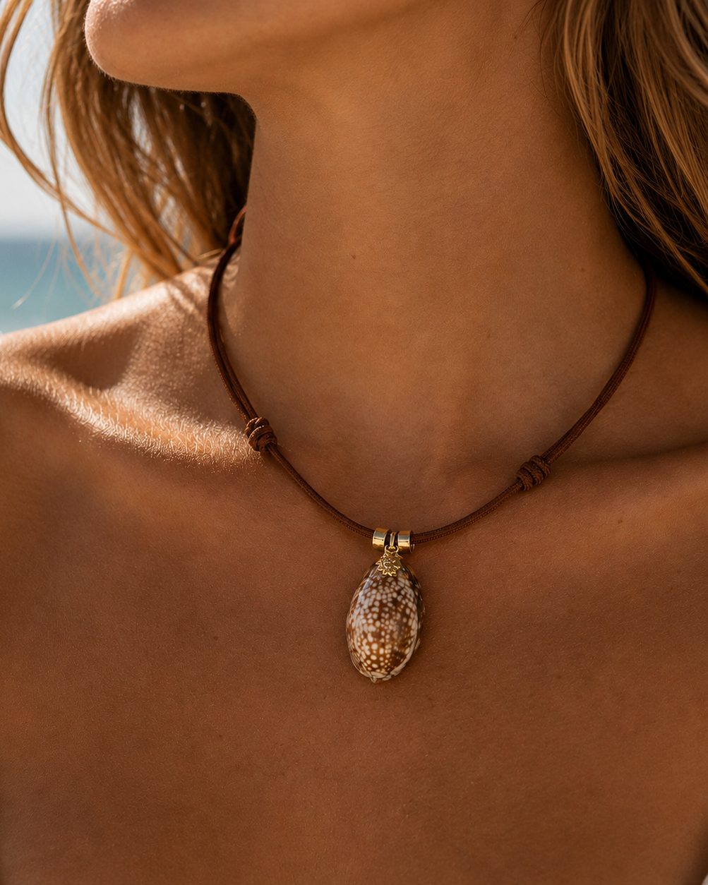 Necklace with a textured pendant worn by a person against a blurred natural background