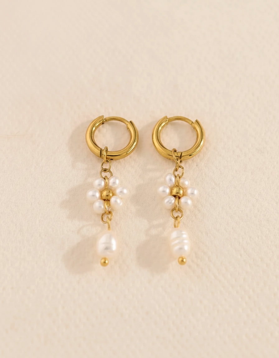 Gold hoop earrings with pearl drops on a beige background