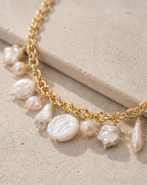 Gold necklace with pearls on a beige stone surface