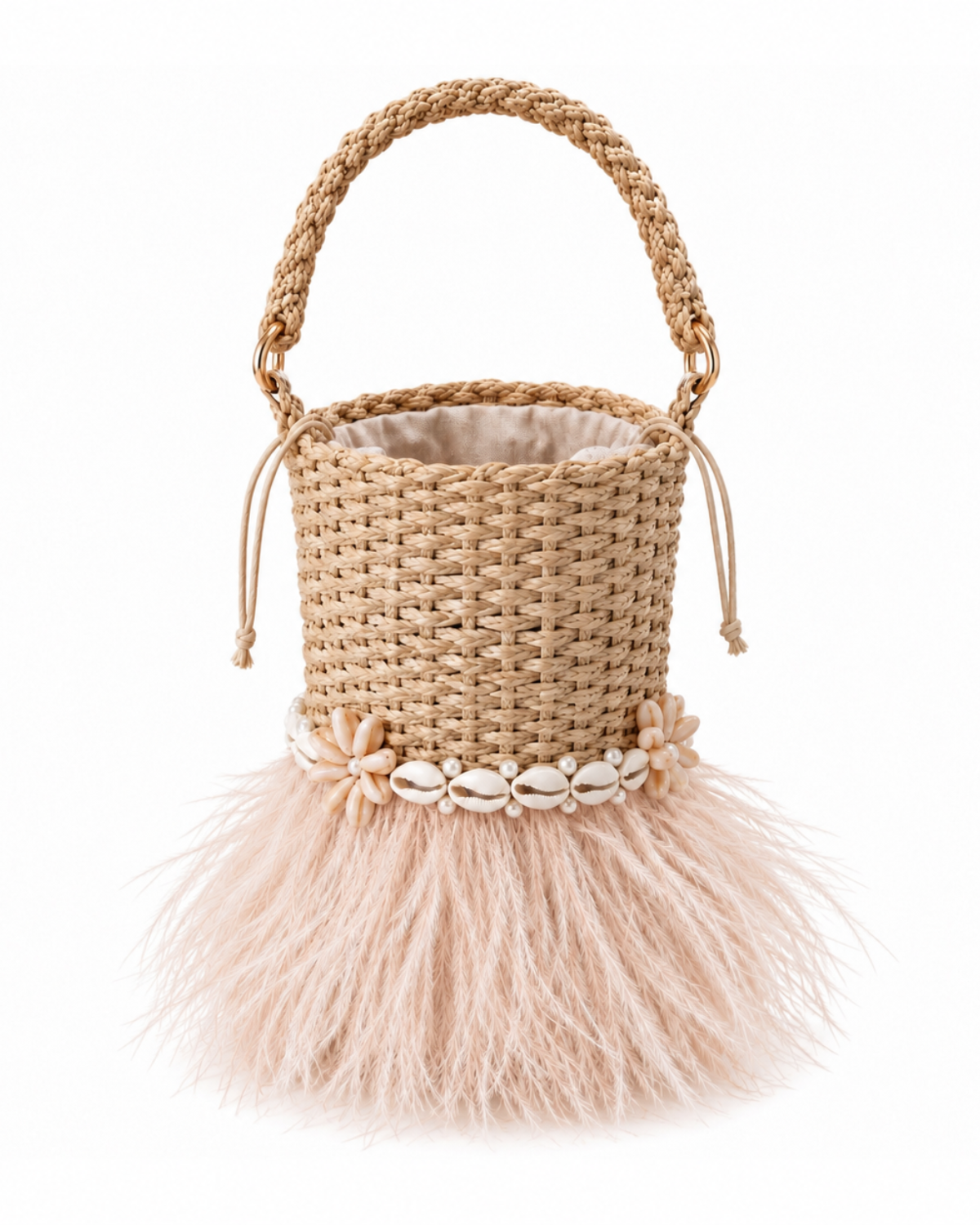 A woven straw bucket bag with a braided top handle, a decorative band of white cowrie shells, and a fluffy blush pink feather skirt, shown on a solid white background.