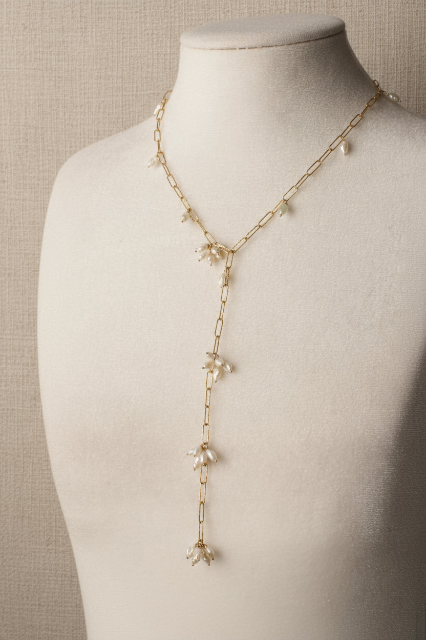 Delicate gold necklace with floral pendants on a mannequin.