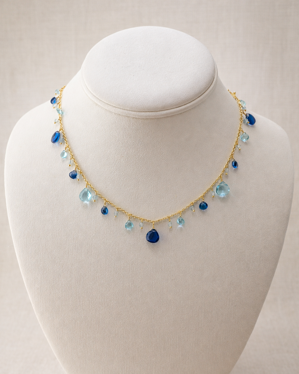Necklace with blue and clear beads on a mannequin bust against a white background