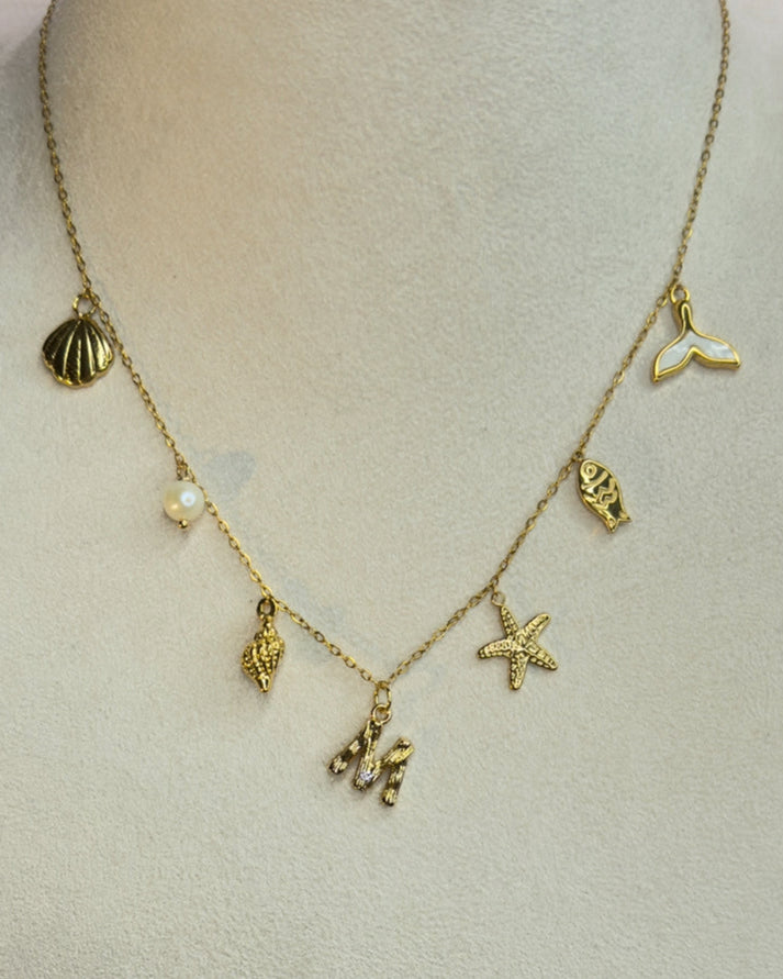 Gold necklace with various charms on a mannequin bust.