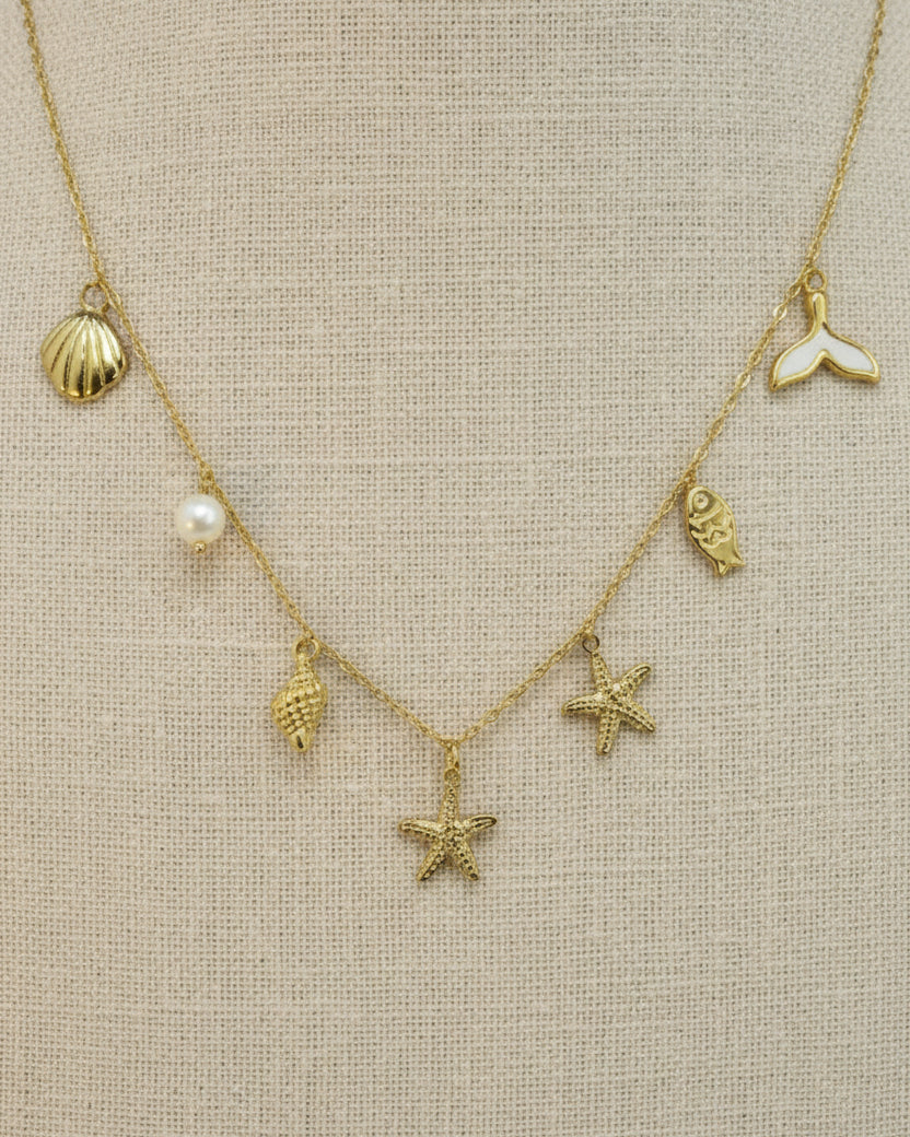 Gold necklace with various charms on a mannequin bust.