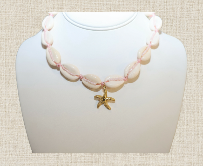 Necklace with shell beads and a starfish charm on a white stand against a beige background