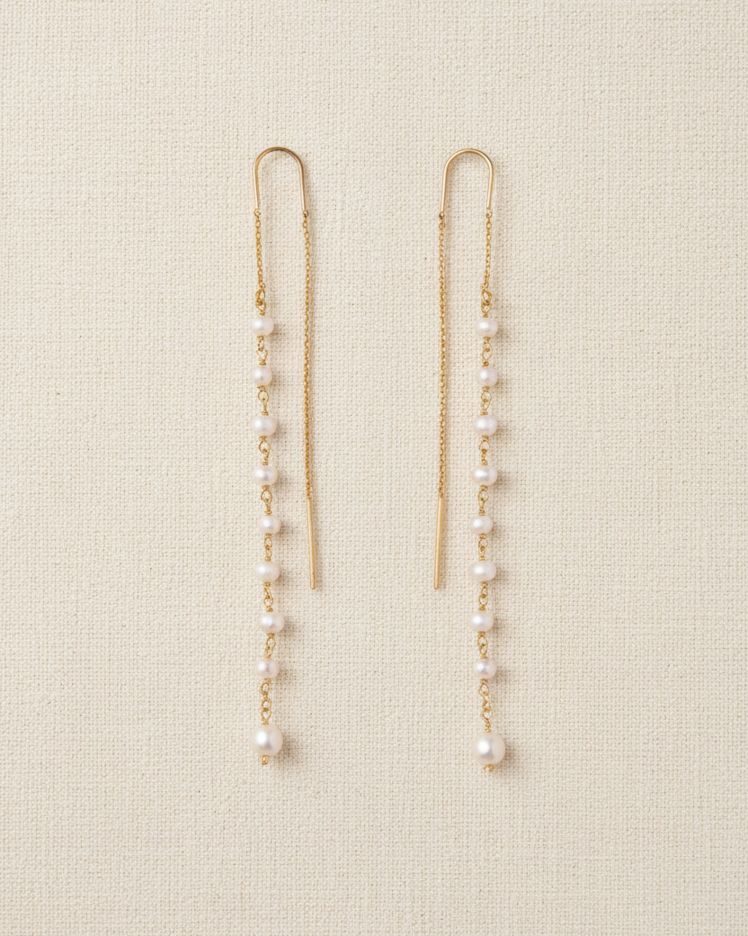 A pair of thread-thru earrings featuring freshwater pearls on an 18k gold plated sterling silver chain.
