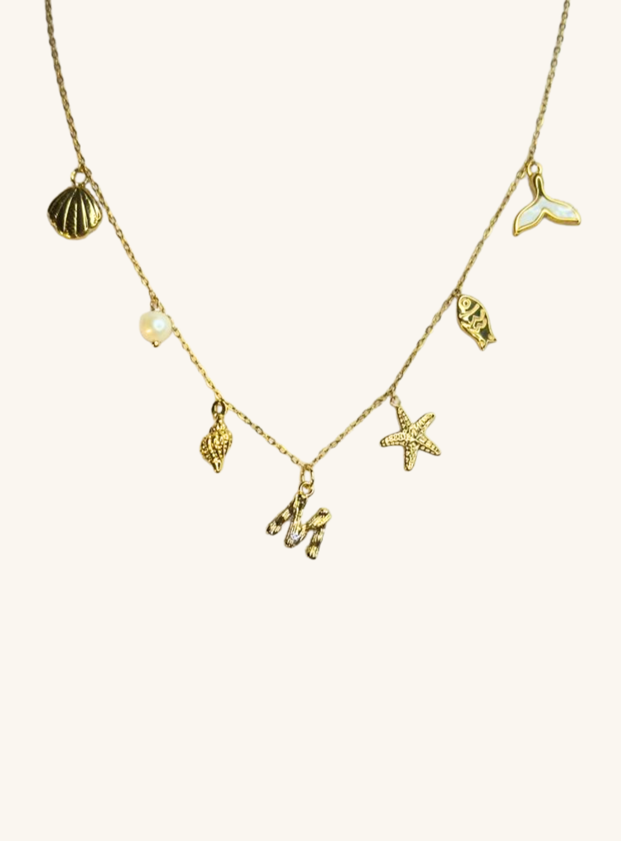 Gold necklace with various sea-themed charms on a white background