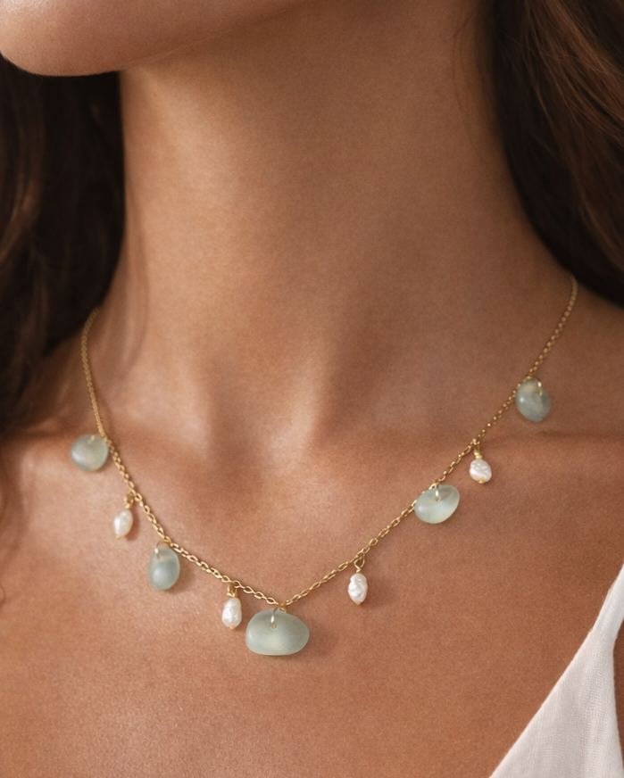 Necklace with green beads and gold chain worn by a person