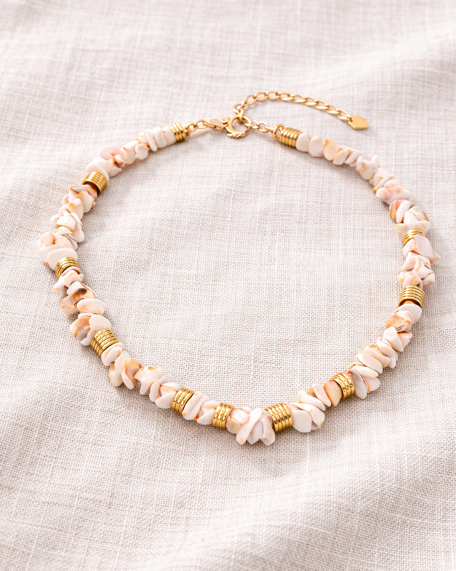 Necklace with pink and gold beads on a light fabric background