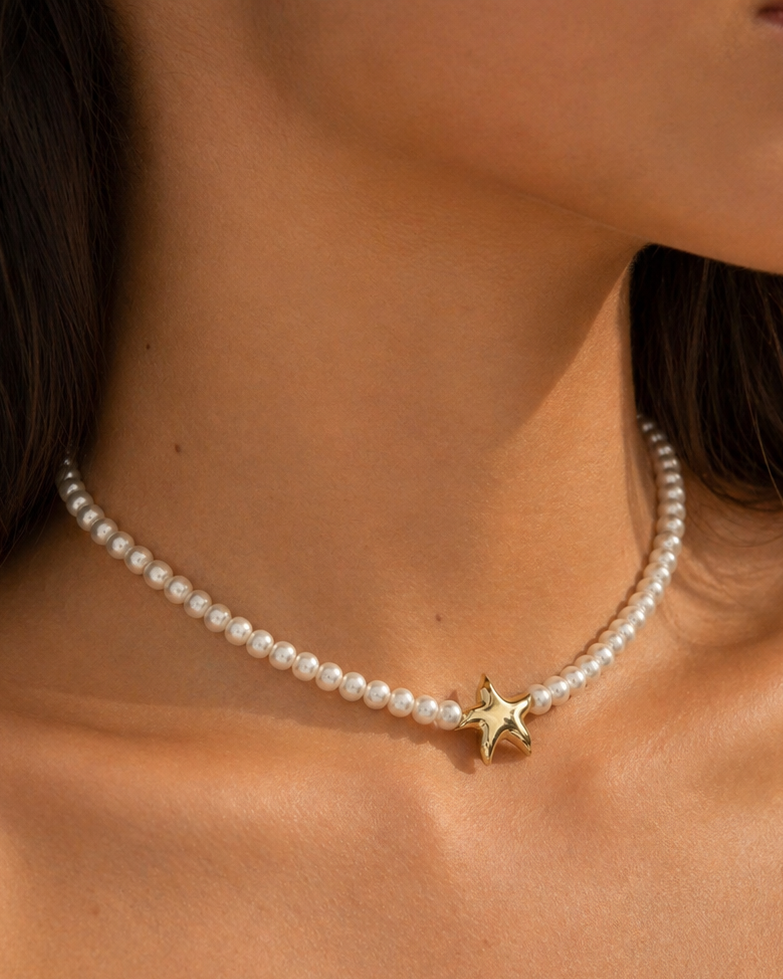 Pearl necklace with a gold star pendant on a person's neck