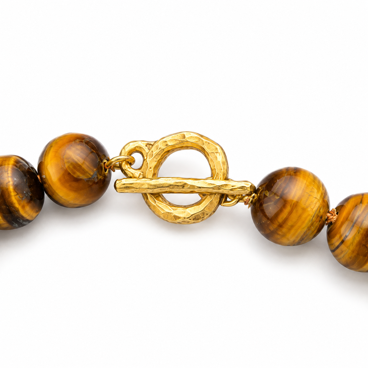 Close-up of a beaded jewelry strand featuring polished round brown and golden-brown tiger's eye beads with a textured hammered gold toggle clasp 